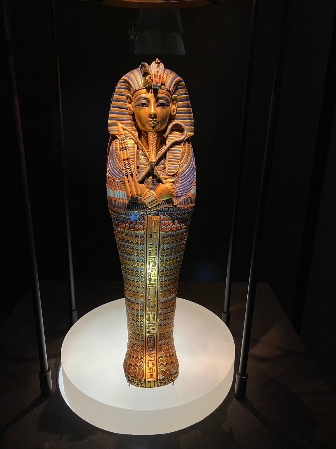 Editorial Egyptian-history photograph of a gold-and-blue decorated coffin-shaped display behind glass