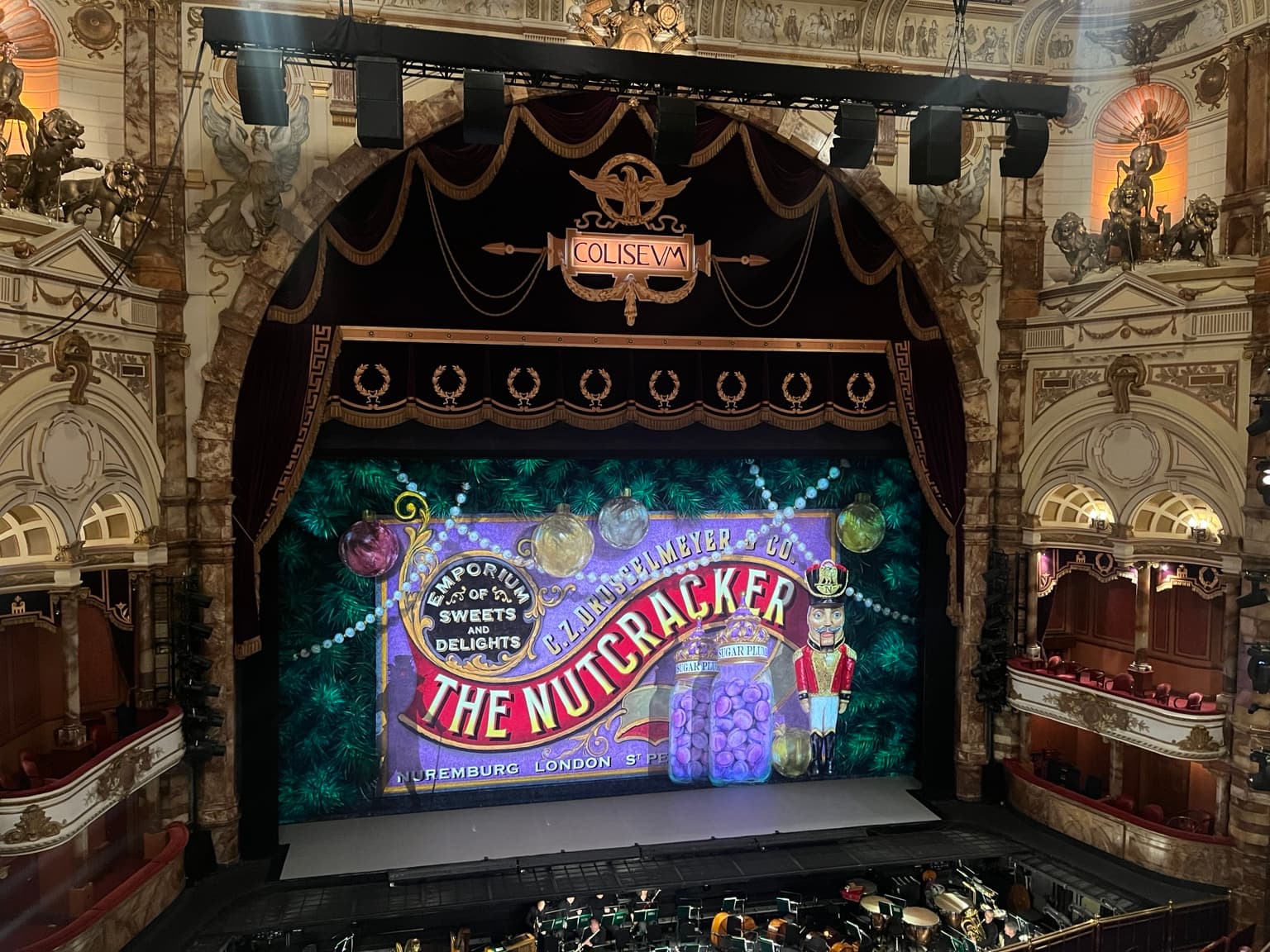 The Nutcracker stage curtain beneath the London Coliseum’s ornate proscenium, with the orchestra pit in the foreground