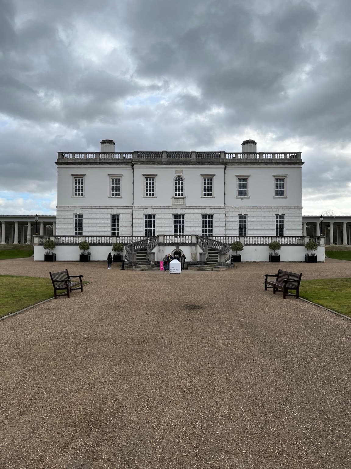 White façade and curved entrance steps of the Queen’s House in Greenwich beneath a cloudy sky