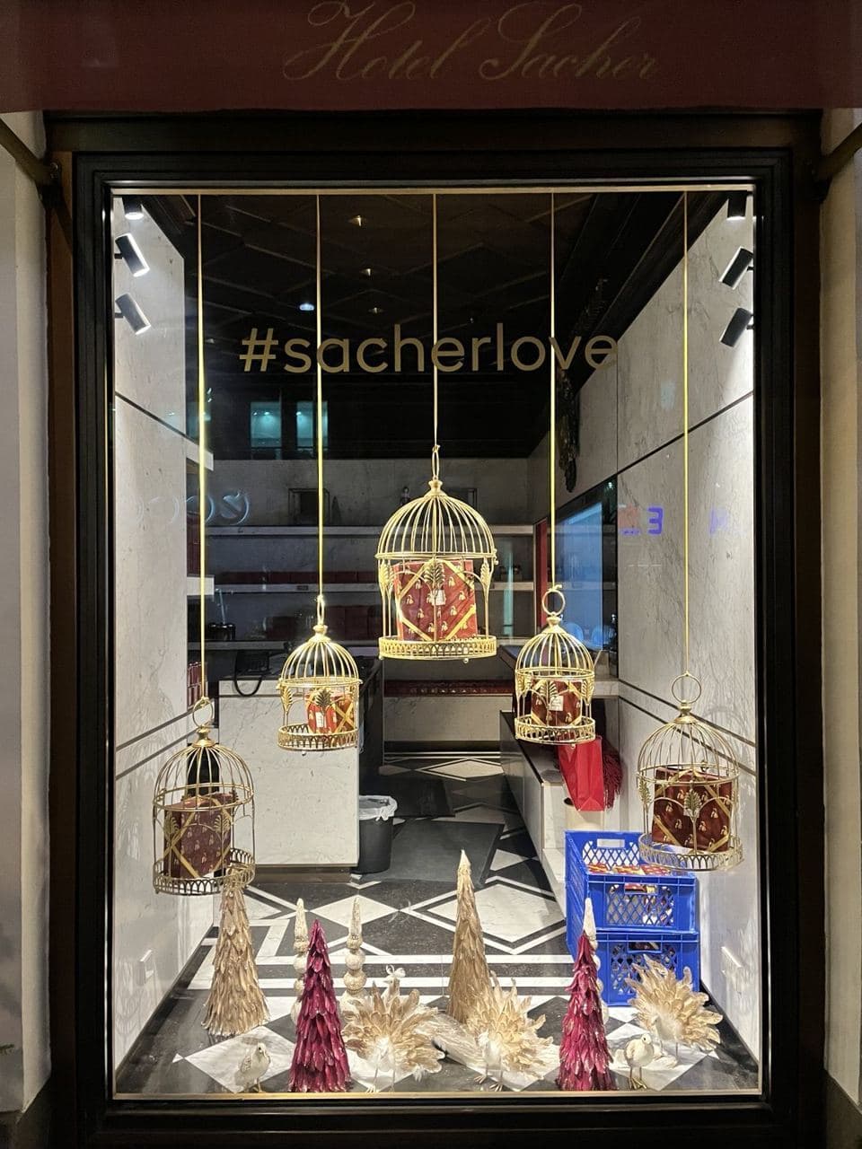 Seasonal Sacher shop window with gold birdcages and gift boxes