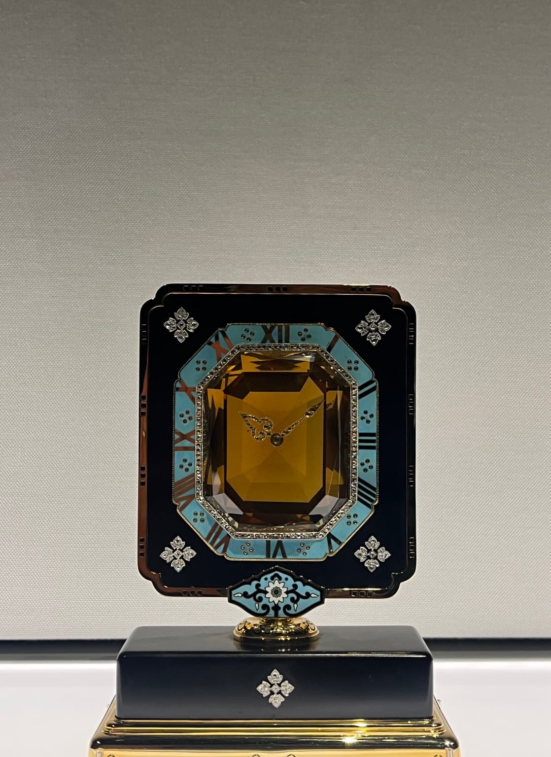 Decorative clock with a turquoise numeral border, amber-coloured centre and black rectangular frame