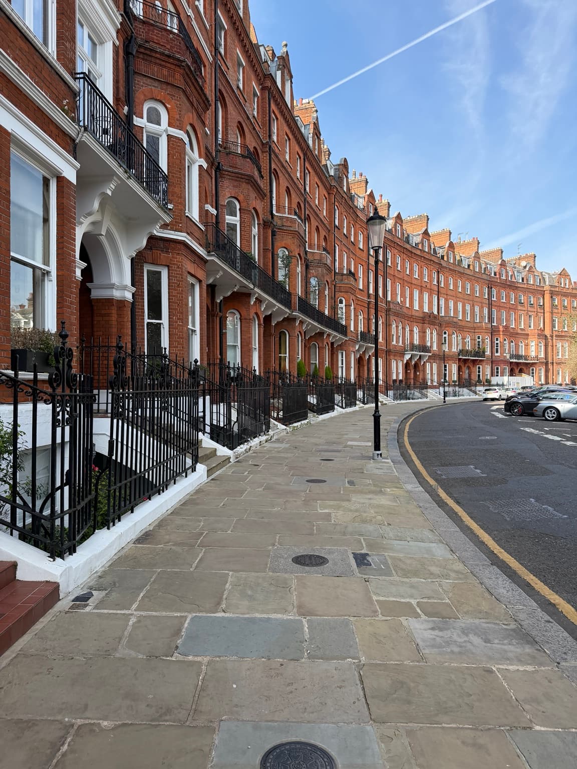 Editorial London photograph of a curved red-brick terrace with iron railings and a street lamp; not The Milestone Hotel & Residences
