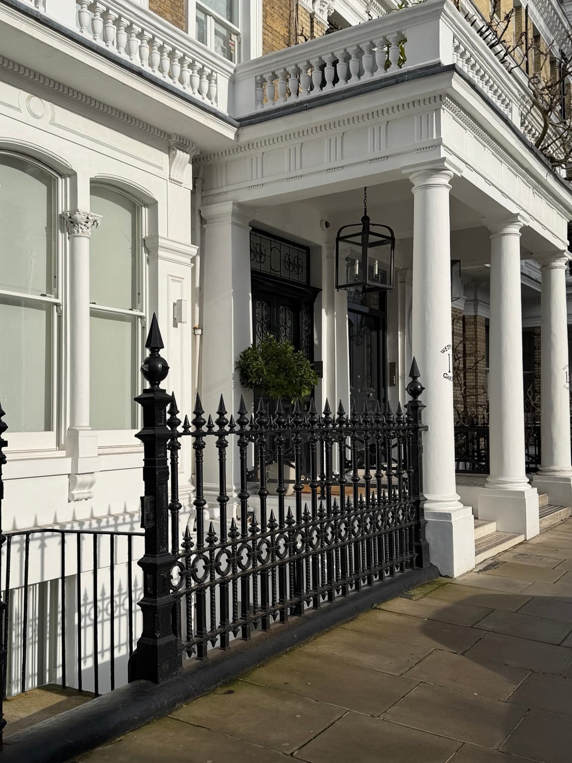 Editorial South Kensington neighbourhood photograph of a white-columned townhouse and black iron railings; not The Kensington hotel