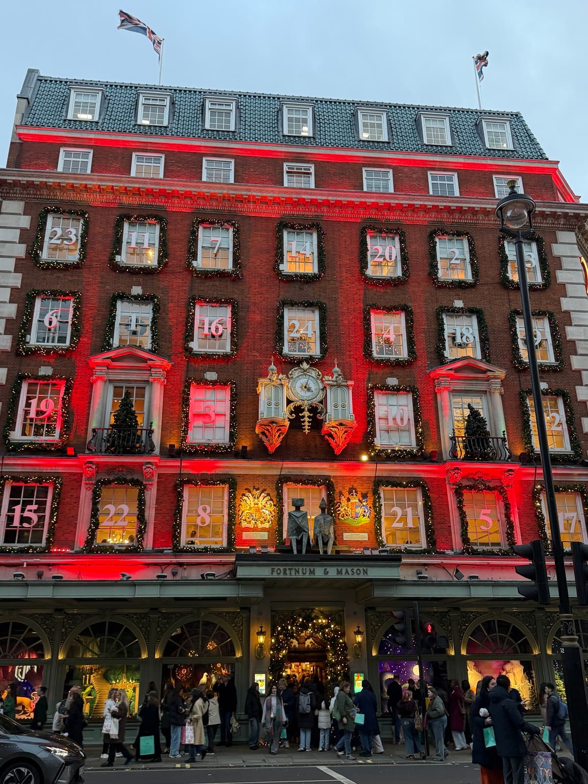 Fortnum & Mason’s Piccadilly façade lit in red, with numbered advent windows, festive garlands and the entrance below its clock