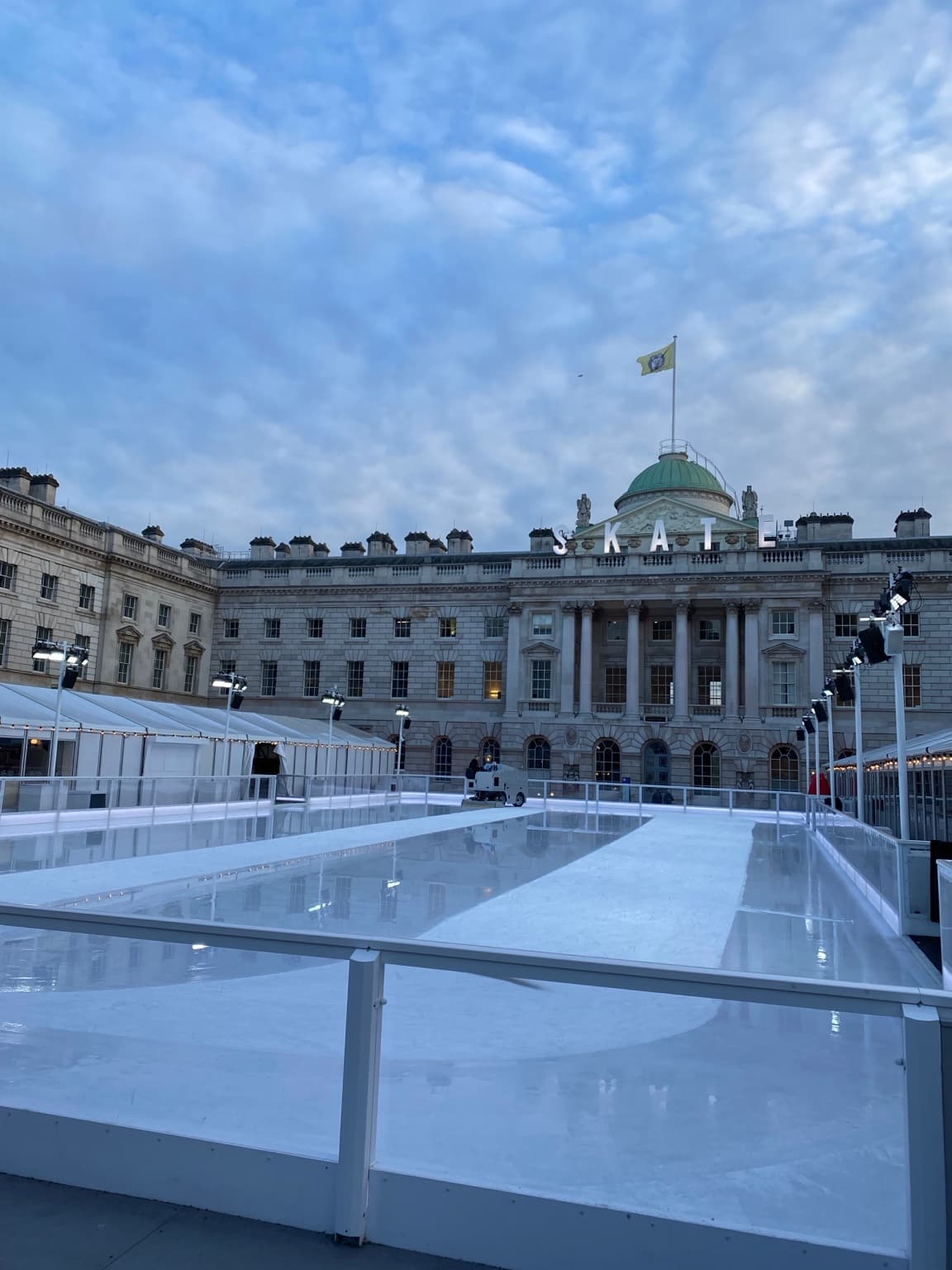 Somerset House courtyard and seasonal ice rink beneath a cloudy blue sky