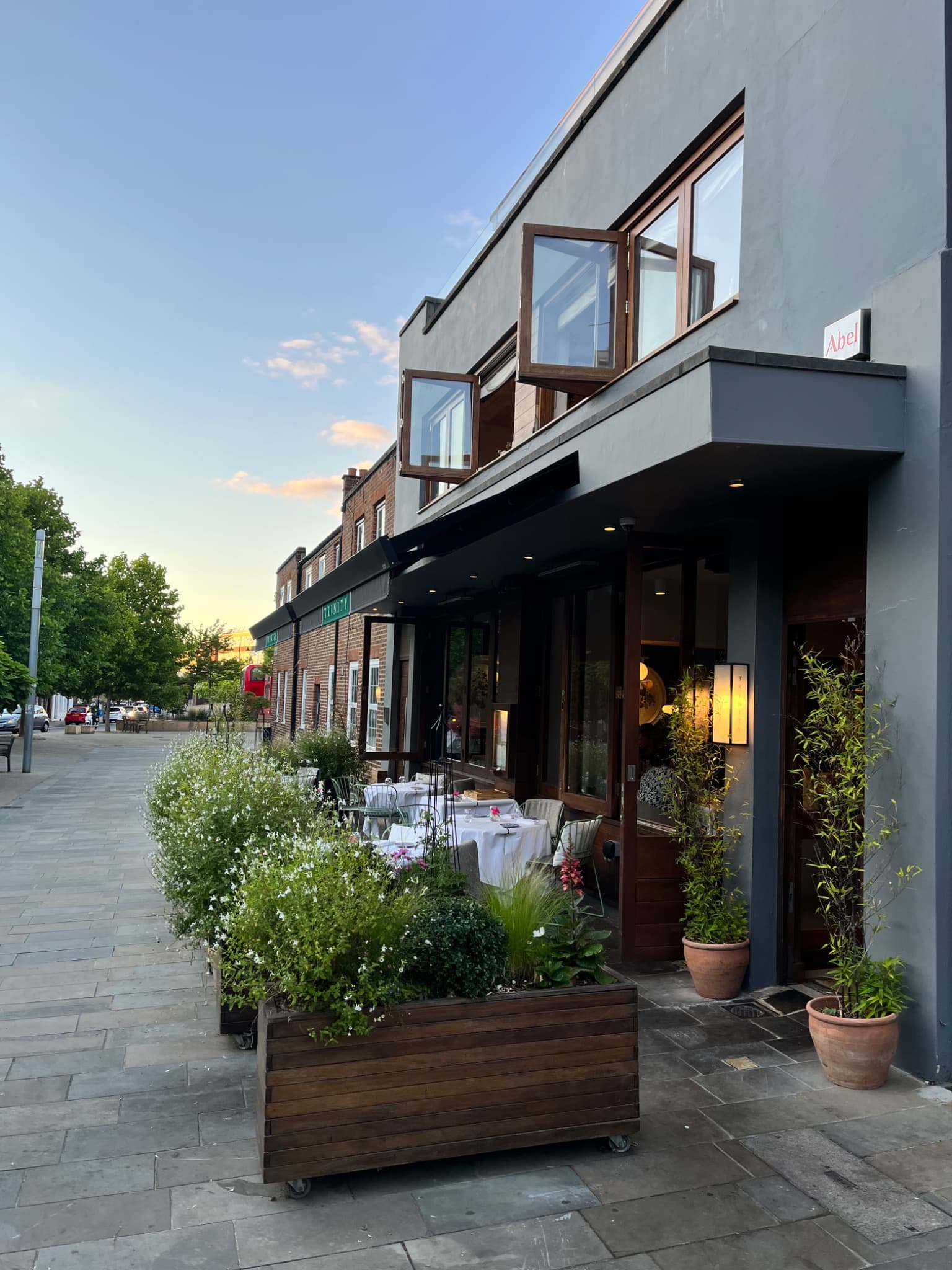 Trinity restaurant exterior in Clapham with a black awning and planted terrace